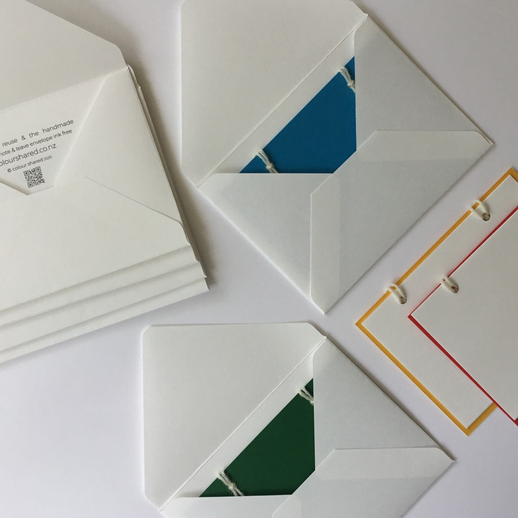 The reusable greeting card. A set of 4 handmade note cards in:  blue, green, red and yellow with 4 handcrafted envelopes. The  back of the cards have 3 note papers.  These are attached with 2 wool loops.
