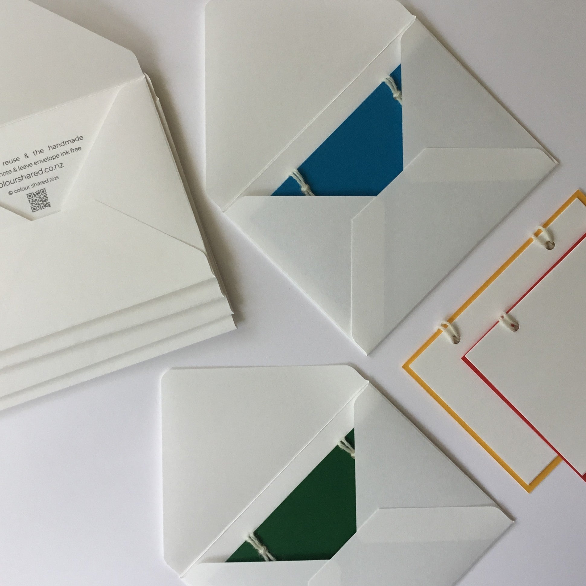 The reusable greeting card. A set of 4 handmade note cards in:  blue, green, red and yellow with 4 handcrafted envelopes. The  back of the cards have 3 note papers.  These are attached with 2 wool loops.
