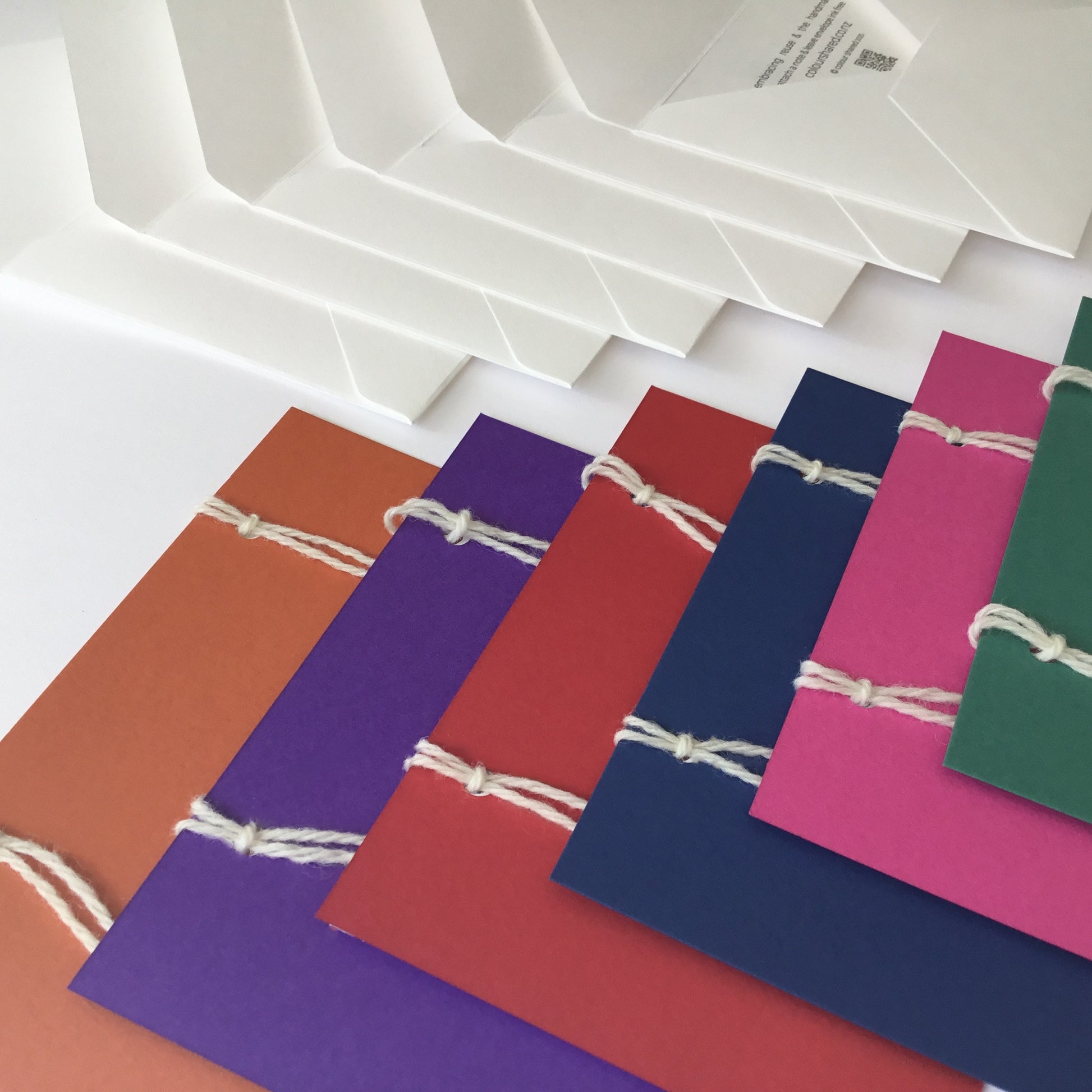 A set of 6 handmade colour cards in: green, pink, blue, red, purple and orange. The set has 6 envelopes. The back of the cards have 3 notepapers.  These are attached with 2 wool loops.